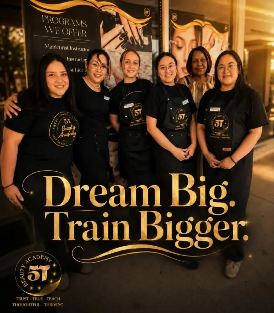 A group of five beauty students and one instructor smiling together in front of a poster listing courses at 5T Beauty Academy.