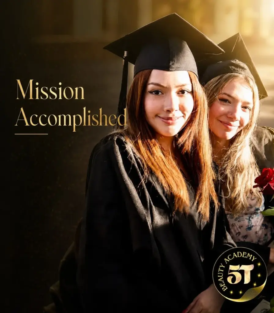 Two female beauty school graduates smiling happily in their graduation caps and gowns