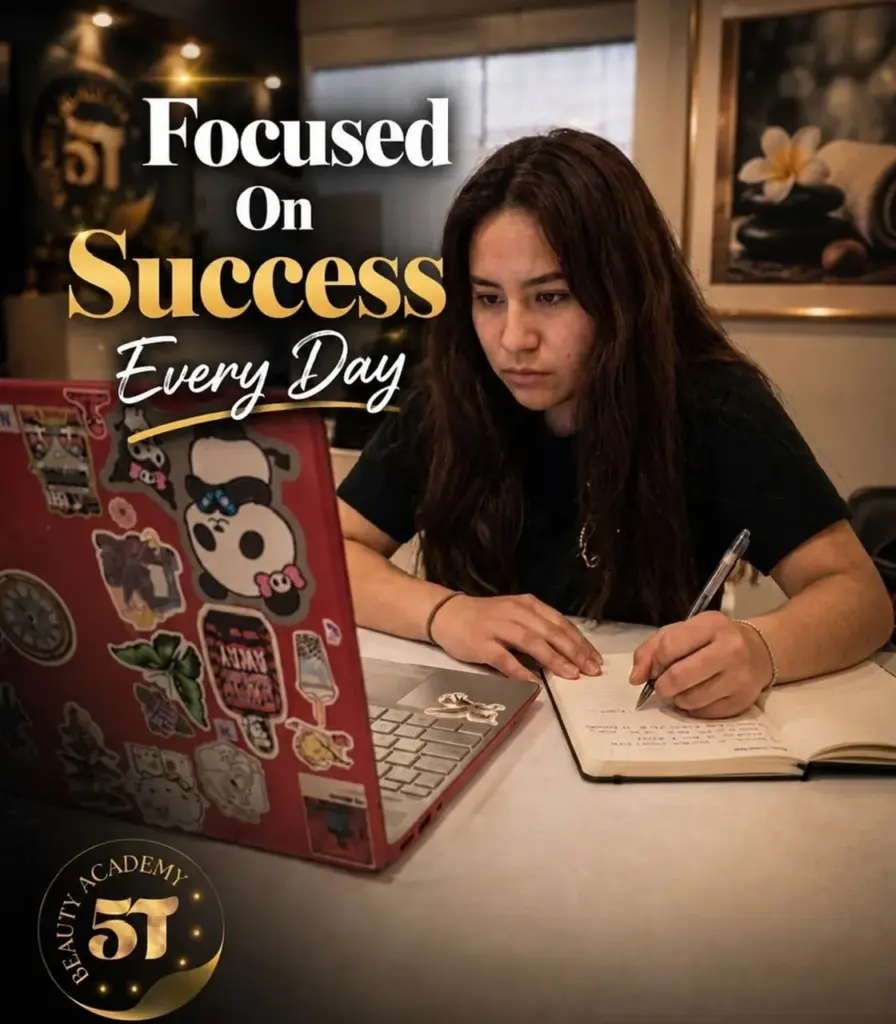 A female student studying with a sticker-covered laptop and writing notes at 5T Beauty Academy.